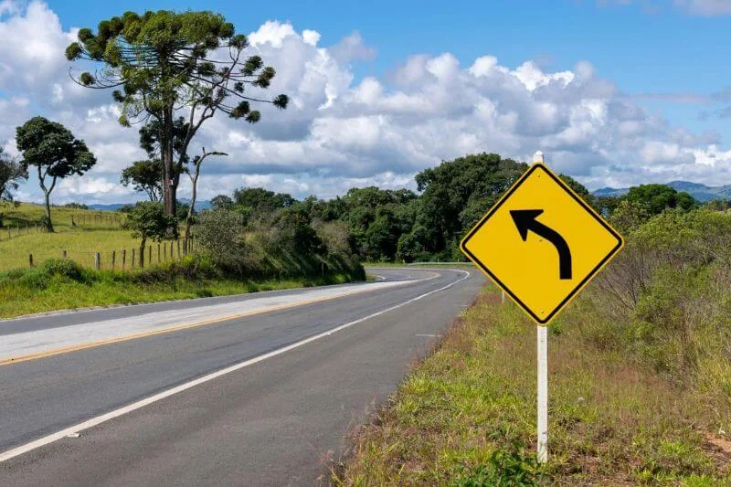 Rodovia com uma placa de trânsito indicando uma curva